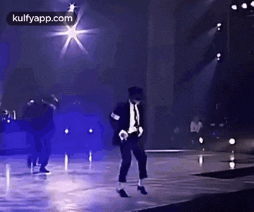 a man in a suit is dancing on a stage .