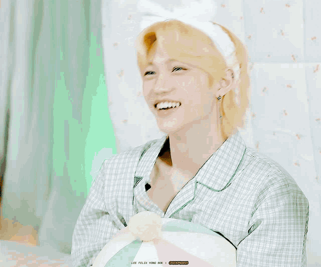 a young man wearing a plaid shirt and a headband smiles