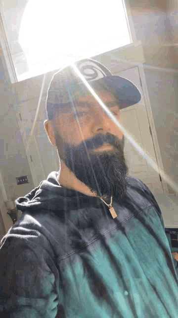 a man with a beard wearing a hat and a tie dye shirt takes a selfie