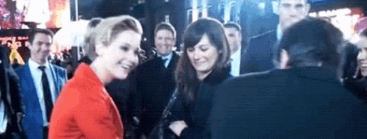 a woman in a red jacket is standing next to another woman in a crowd .