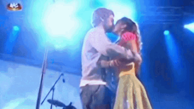 a man and woman are kissing on a stage in front of a microphone .