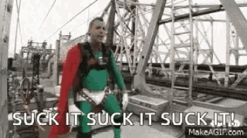 a man in a superhero costume is standing in front of a bridge .