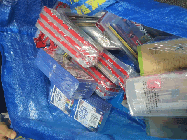 a blue bag filled with school supplies including colored pencils and erasers