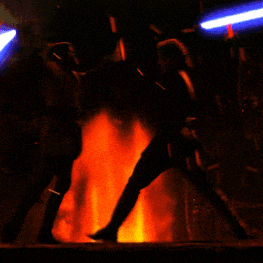 two people standing in front of a large fire