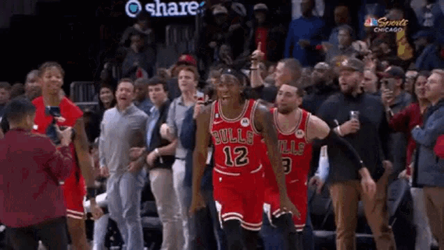 a group of people are standing around a basketball player wearing a bulls uniform .
