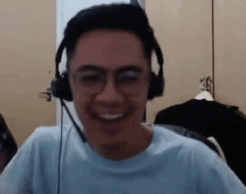 a man wearing headphones and glasses is smiling in a room .