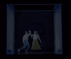 a man and a woman are dancing in a room with blue lights