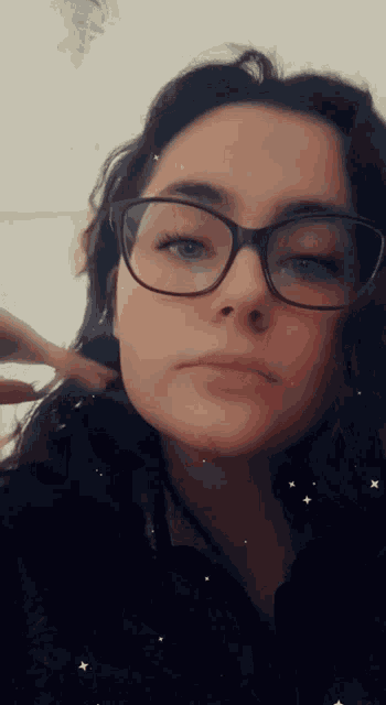 a woman wearing glasses looks at the camera