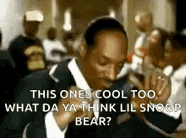 snoop dogg is wearing a suit and tie and talking into a microphone in a crowded room .