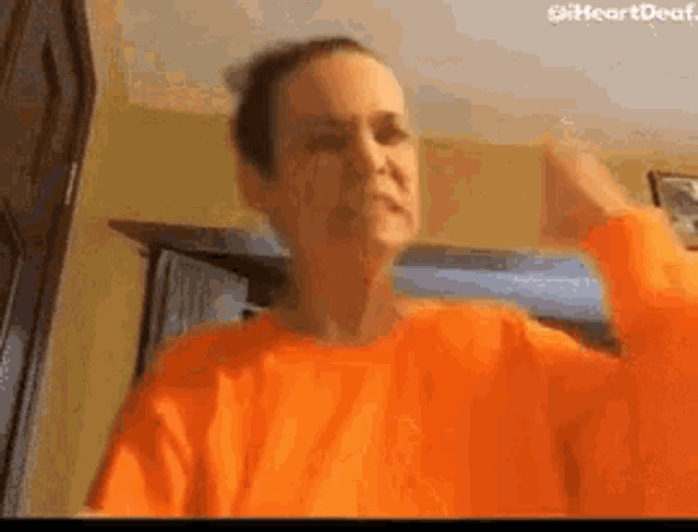 a woman in an orange shirt is making a funny face .