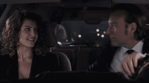 a man and a woman are looking at each other in a car .