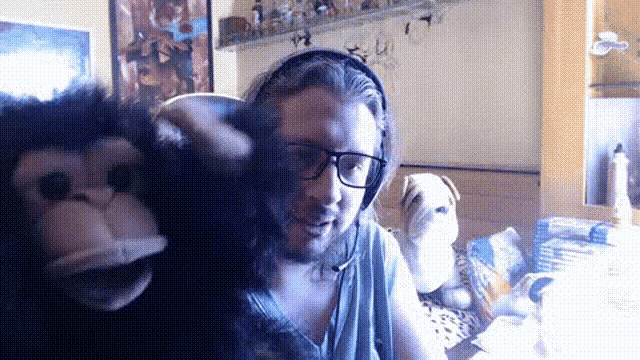 a man wearing glasses and headphones is holding a stuffed animal