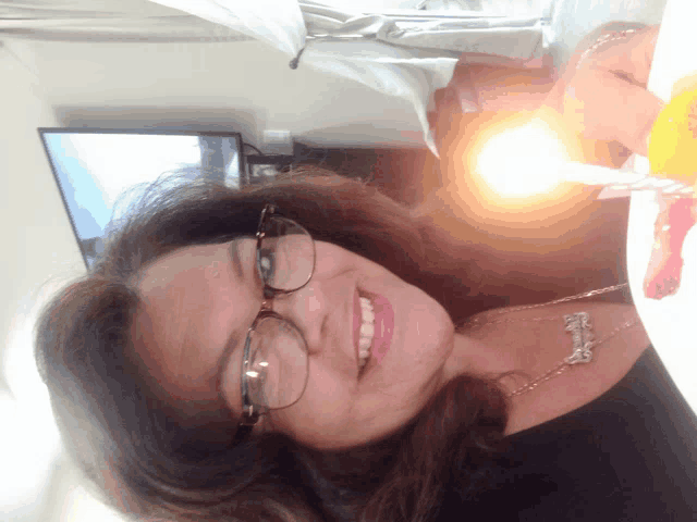 a woman wearing glasses and a necklace that says ' elizabeth ' on it