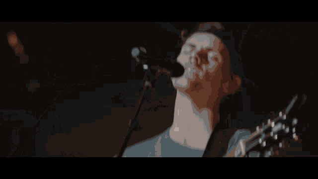 a man singing into a microphone with his eyes closed