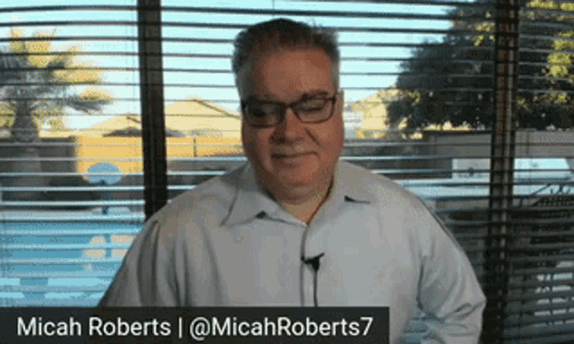 a man standing in front of a window with the name micah roberts written on the bottom