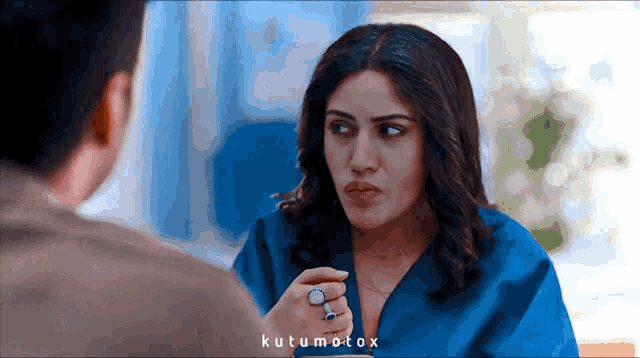 a woman with a ring on her finger talks to a man in a blue shirt