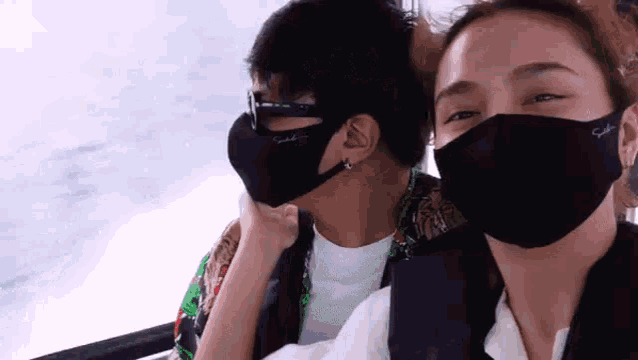 a man and a woman are wearing face masks while riding a boat .