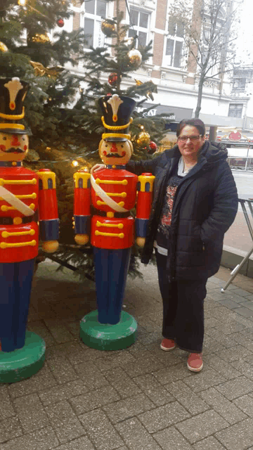 a woman stands in front of a nutcracker statue