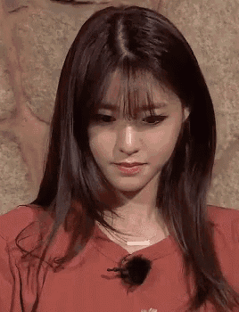 a close up of a woman with long hair and bangs wearing a red sweater .