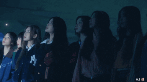a group of girls are standing in a row with one wearing a jacket that says ny on it