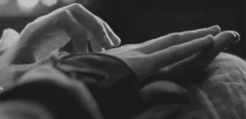 a black and white photo of a person 's hands touching another person 's hand .