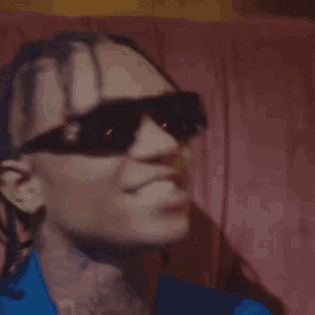 a man wearing sunglasses and a blue shirt is smiling and looking at the camera .