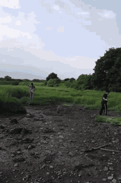 a couple of people standing in a field with trees