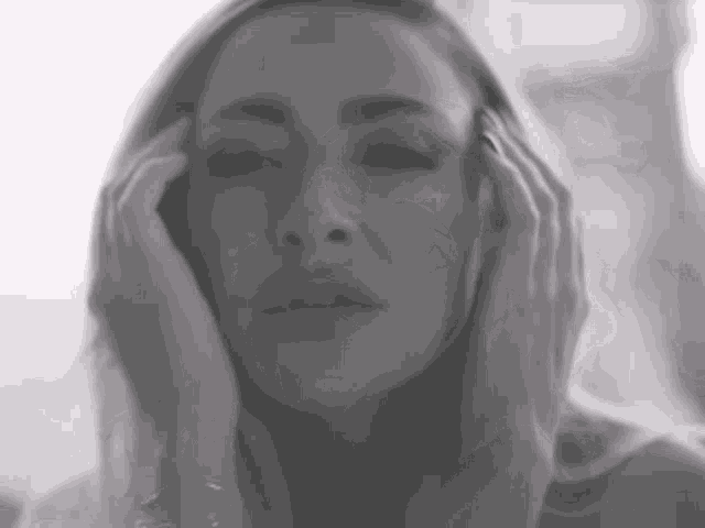 a close up of a woman 's face with her hands on her face