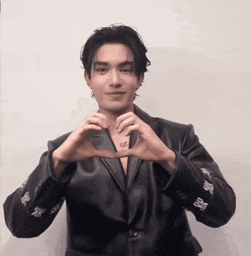 a man in a black leather jacket making a heart shape with his hands