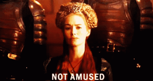a woman wearing a crown says not amused in front of a man in armor