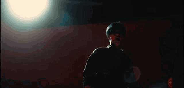 a man in a dark room with a light shining on his face