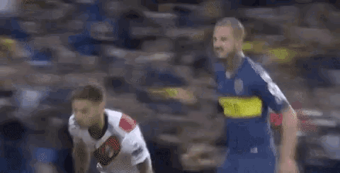 two men are playing soccer on a field and one is wearing a qatar shirt .