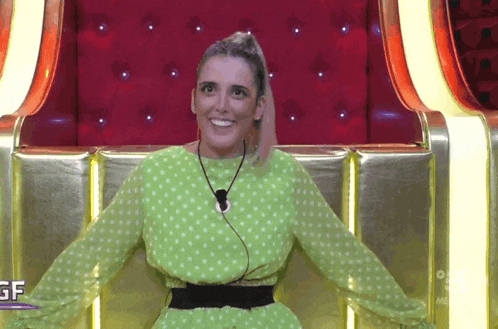 a woman in a green polka dot dress sits in a chair with the letters gf on the bottom