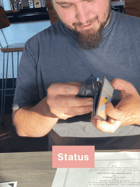 a man sits at a table with a menu and a card that says status