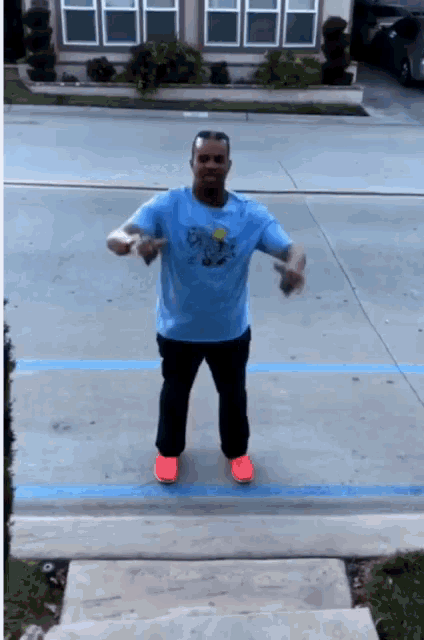 a man wearing a blue shirt that says ' simpson ' on it is dancing in a parking lot