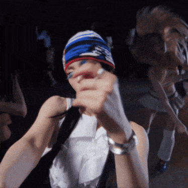 a woman wearing a blue white and red beanie is dancing in a dark room