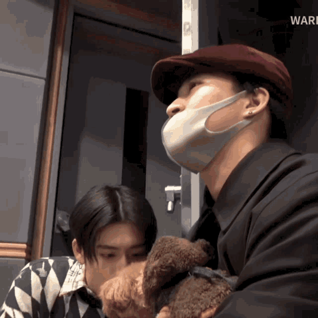 a man wearing a mask holds a small brown dog
