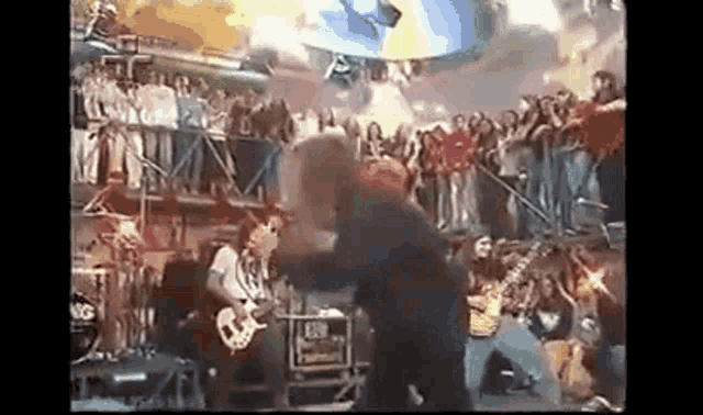 a man is playing a guitar on a stage in front of a crowd of people .