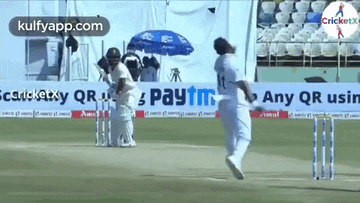 a cricket player is jumping in the air in front of a paytm sign .