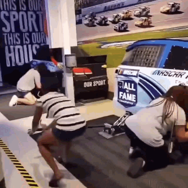 a group of people are working on a race car in a room .