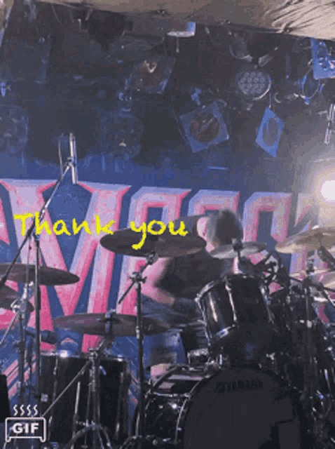 a man playing drums in front of a sign that says ' thank you '
