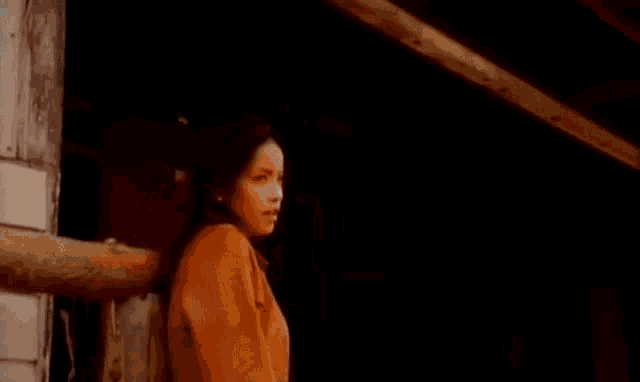 a woman in a brown jacket is standing in front of a door .