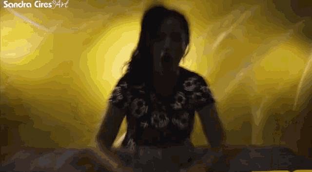 a woman is screaming in front of a yellow background with the name sandra cires written on the bottom