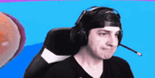 a man wearing headphones and a hat is sitting in a chair with a microphone on his head .