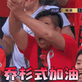 a man in a red shirt is raising his arms in the air in a crowd of people .