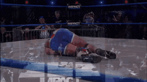 a wrestler is laying on the ground in a wrestling ring with the word impact on the ring .