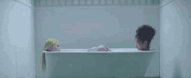 two women are taking a bath in a bathtub .