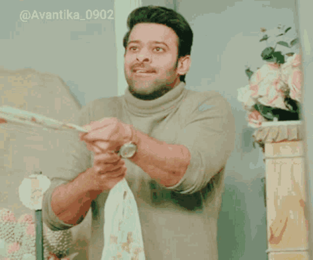 a man in a turtleneck sweater is holding a piece of cloth in his hands