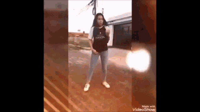 a girl is dancing on a dirt road in front of a house .