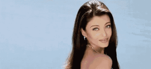 a woman with long hair is wearing a necklace and smiling .